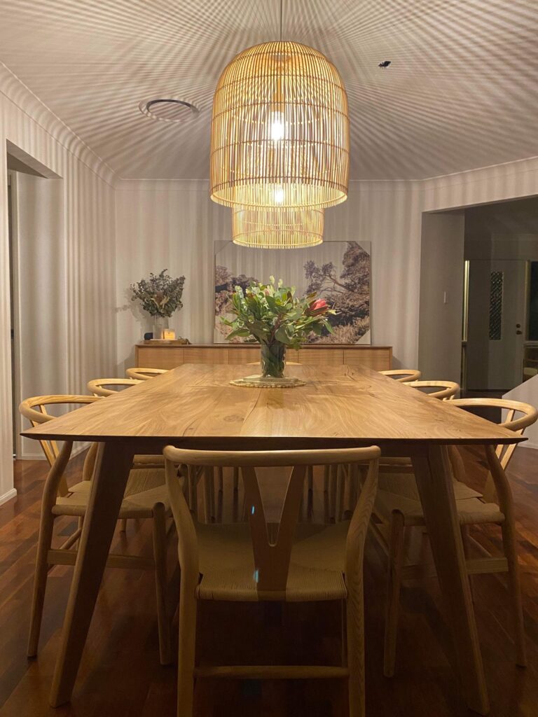 Modern dining room with wooden table and pendant lights.