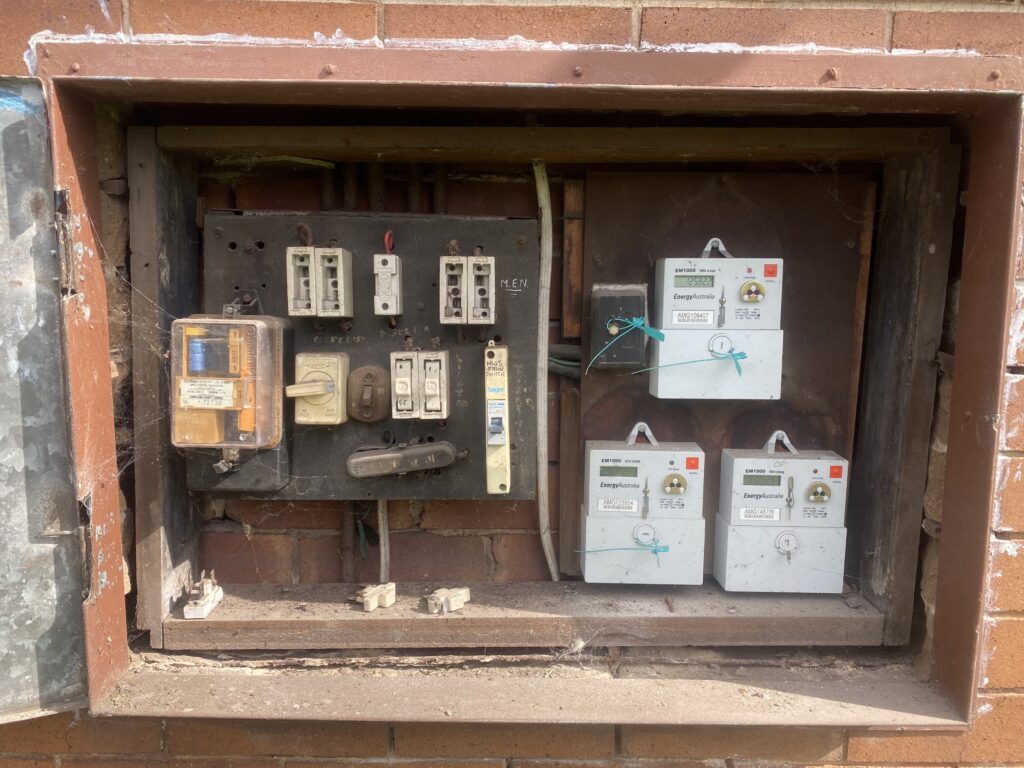 Electric meter and circuit breakers on exterior wall.