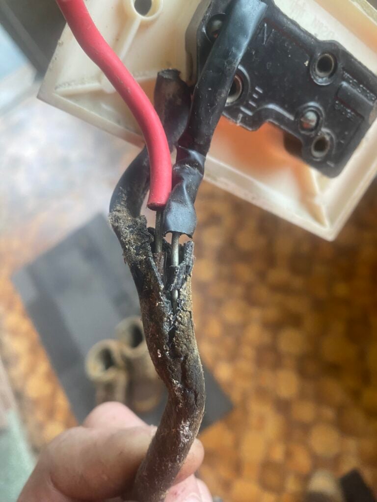 Damaged electrical wire connection showing exposed wires.