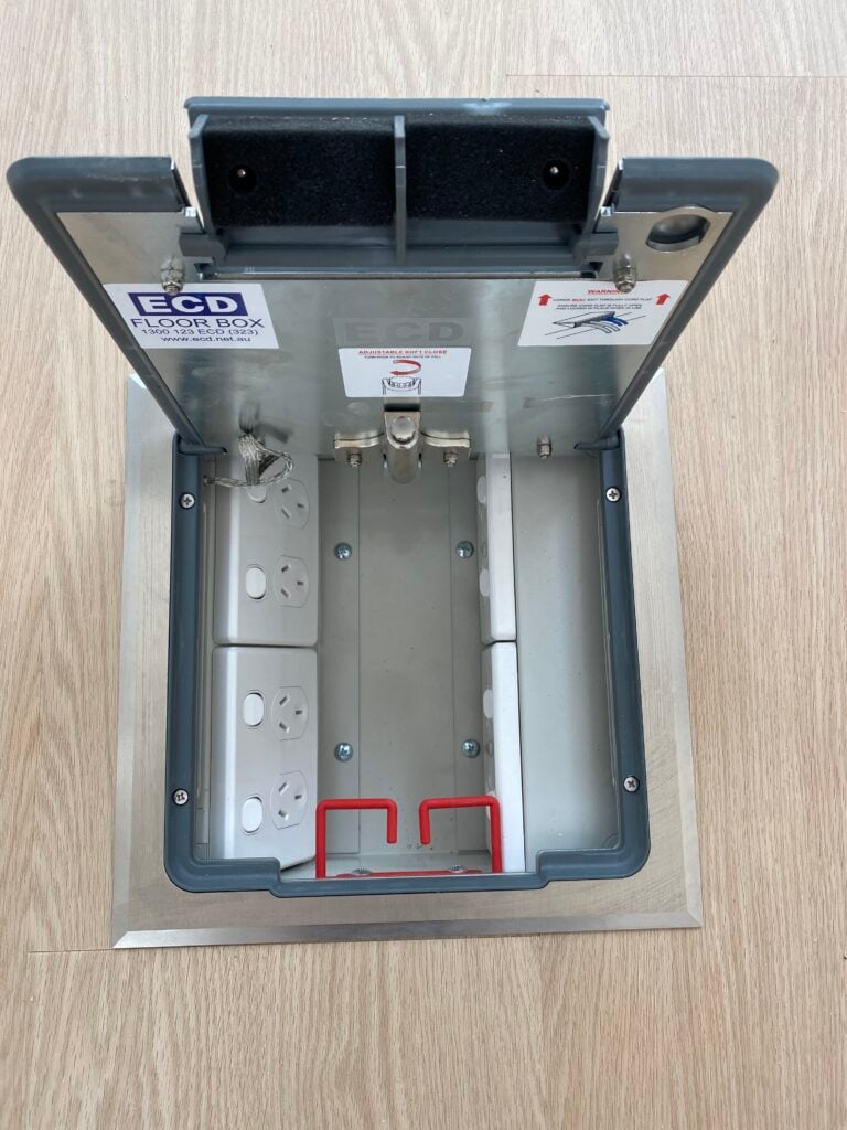 Open floor box with electrical sockets visible.